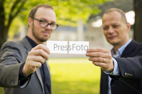 Two smart casually dressed businessmen presenting their business cards to a new network