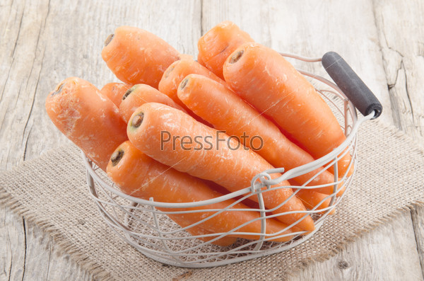organic fresh carrots in a small basket on jute