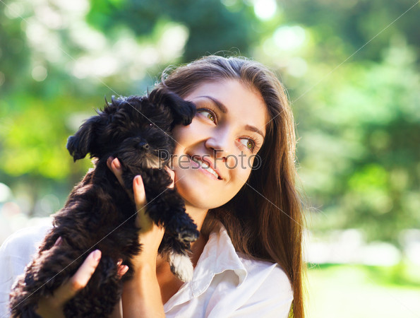 Young brunette woman hugging her lap black dog puppy