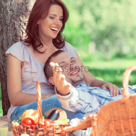 Adult couple picnicking in the park under the tree. Retro style photo