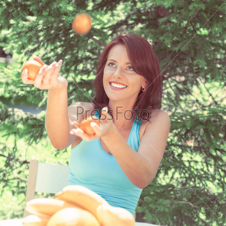Happy Smiling Young Woman Juggling Oranges at her Garden. Retro retouch photo