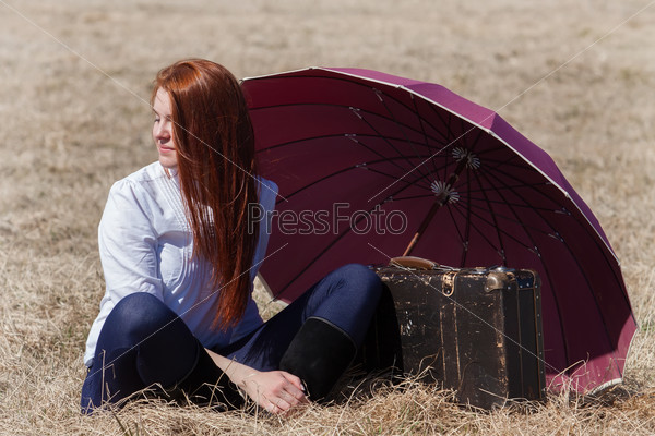 Red haired girl with vintage bag and umbrella
