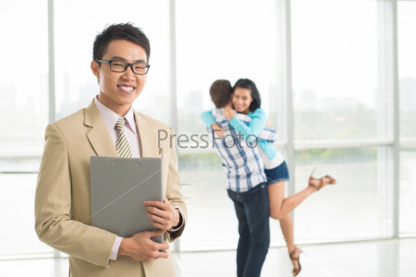 Smiling broker against background of happy embracing family