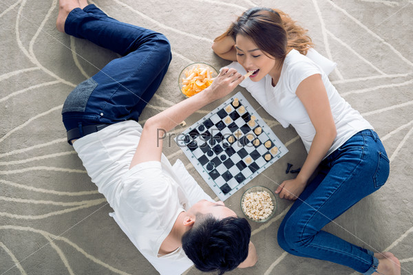 Vietnamese couple lying on the floor and playing chess