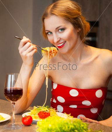 Женщина ест спагетти на кухне