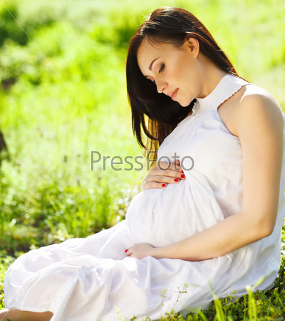 Portrait of beautiful pregnant woman in the spring park