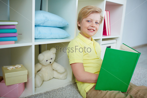 Portrait of clever boy reading book at home