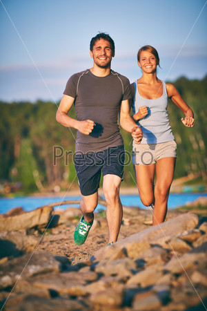Photo of happy young couple running outdoors
