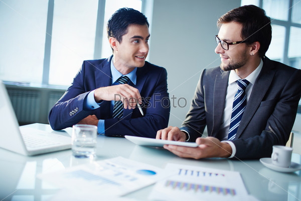 Image of two young businessmen communicating at meeting