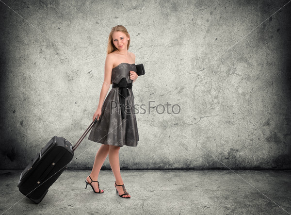 Full body portrait of young female in dress standing with her travel bag