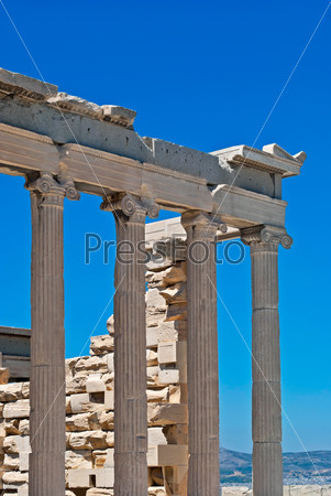 Fragment of the ruins of an ancient temple of the Acropolis in Athens, with columns and a fragment of a ruined wall on the sky background.