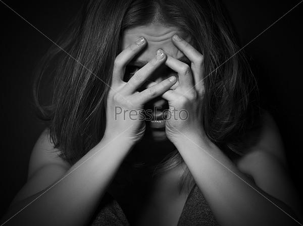 Sad woman in depression and despair crying covered her face on black dark background, stock photo