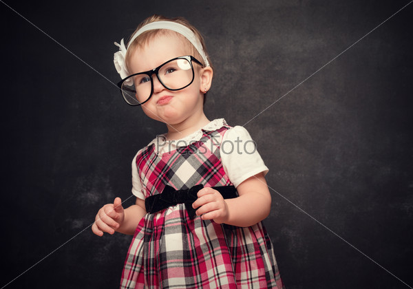 Funny girl pupil in glasses at blackboard