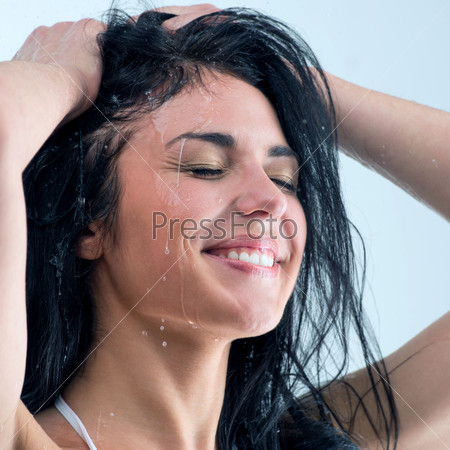 Woman washing her head while showering with happy smile and water splashing.