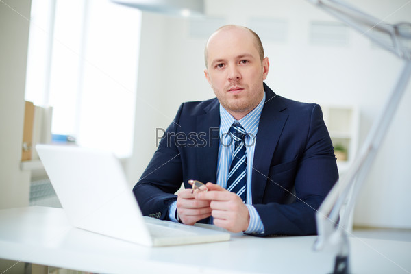 Handsome businessman in smart suit looking at camera in office