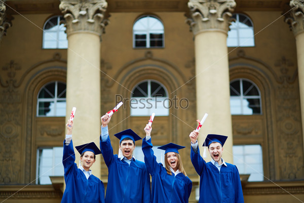 Group of smart students in graduation gowns showing their certificates