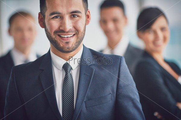 Portrait of confident business partners looking at camera with smiling leader in front, stock photo
