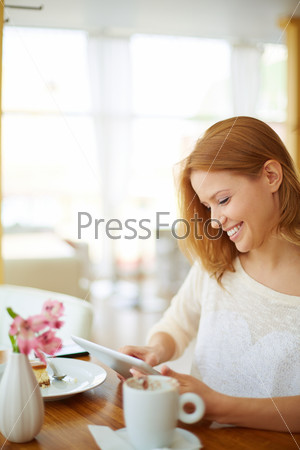 Image of young female using touchpad while sitting in cafe