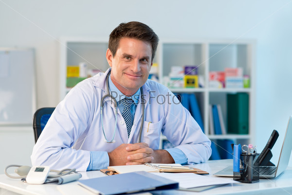 Portrait of general practitioner sitting at the table in his office