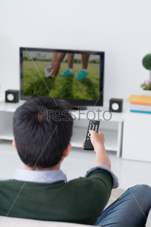 Man watching television in the living room, rear view