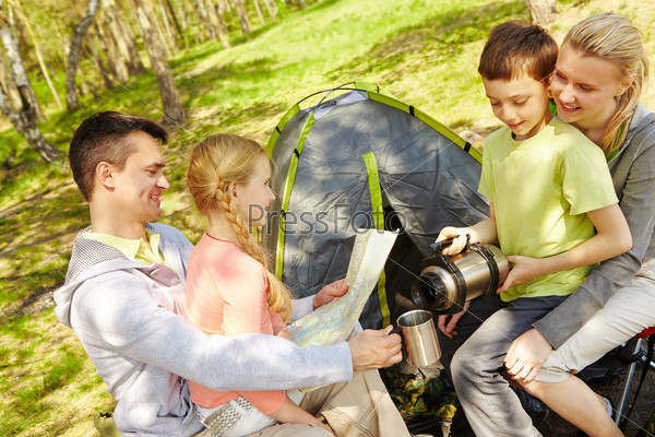 Portrait of family of travelers spending time in forest with tent near by