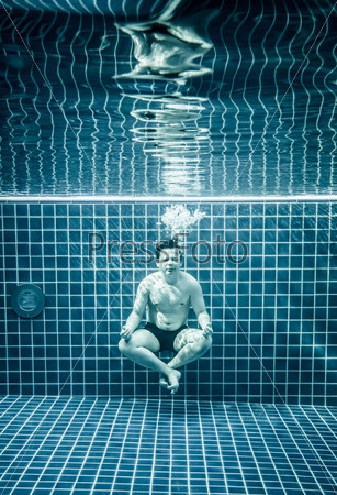 Man under water in a swimming pool to relax in the lotus position