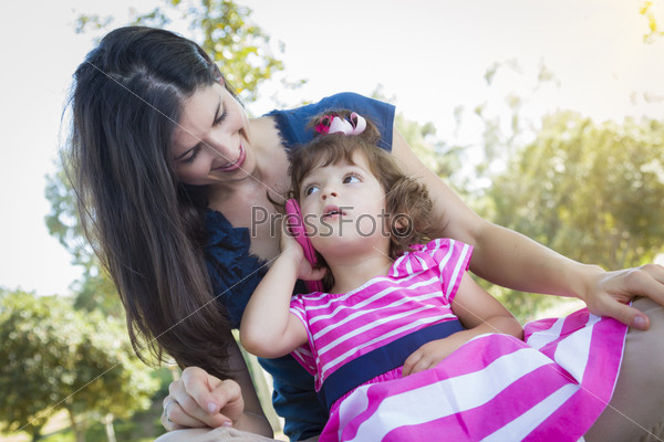 Mixed Race Mother and Cute Baby Daughter Playing with Cell Phone in Park, stock photo