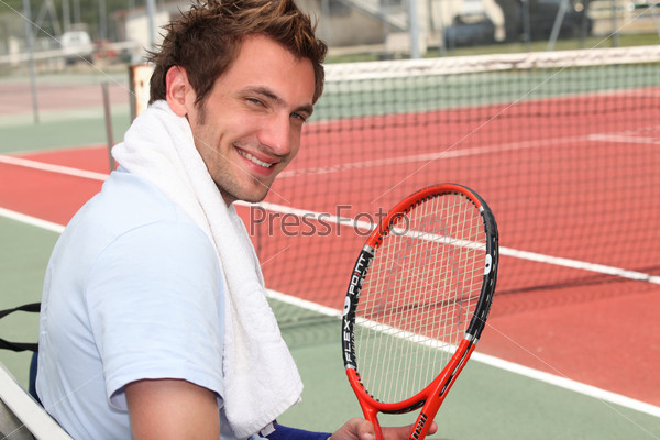 Young tennis player sitting on the court sidelines