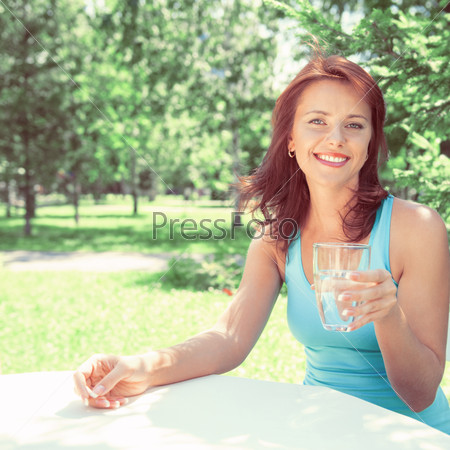 Portrait of young beautiful woman drinking water on picnic at summer green park. Retro retouch photo