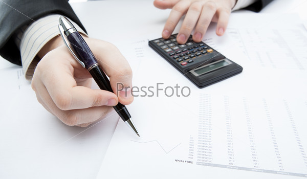 businessman holding a pen and counts the budget on the desktop