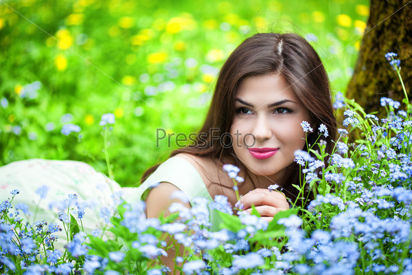 Young woman is lying on field with forget-me-not