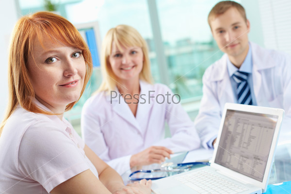 Portrait of female patient looking at camera on background of two practitioners