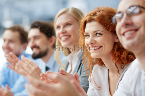 Photo of happy business people applauding at conference, focus on smiling female