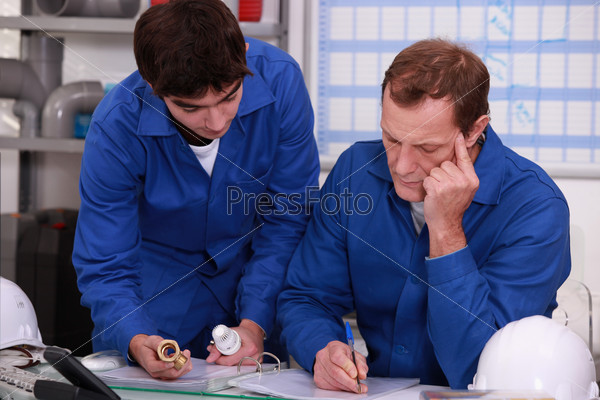 Co-workers checking reference of a piece