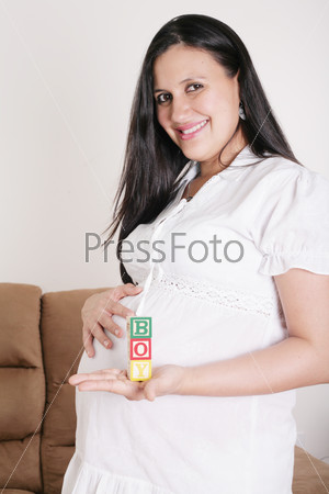 Beautiful hispanic pregnant woman having the word boy with wooden cubes in her hand