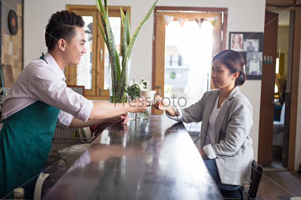 Man serving coffee to the lady in the cafe