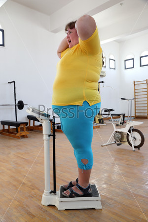 impressed overweight woman on scales in gym