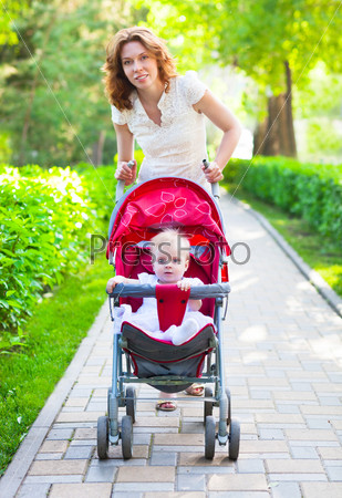 Beautiful young woman with her child in a baby carriage