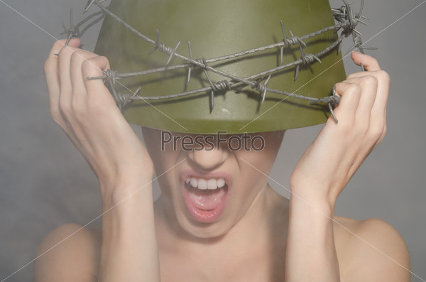 young woman the military helmet with barbed wire screams