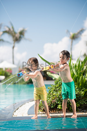 Little brothers playing with water toy in the swimming pool