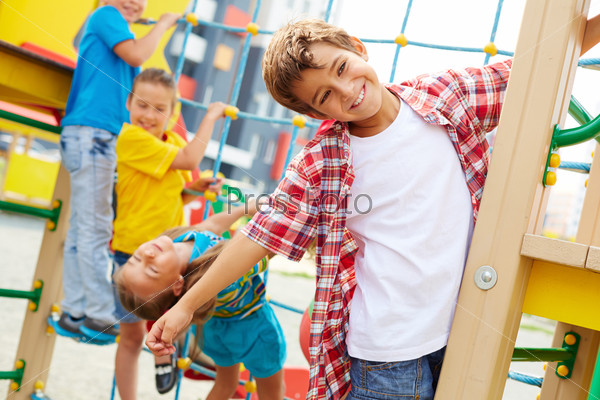 Image of cute kids having fun on playground outdoors, focus on smiling boy