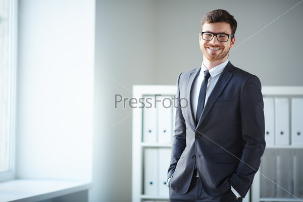 Handsome businessman in suit and eyeglasses looking at camera in office