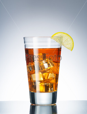 close up view of a glass with iced tea and lemon on blue back