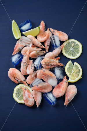Frozen shrimps with ice cubes, lemon and lime slices, above view