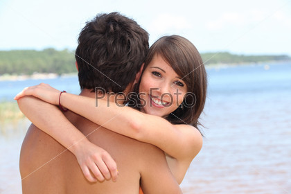 young woman hugging boyfriend at beach