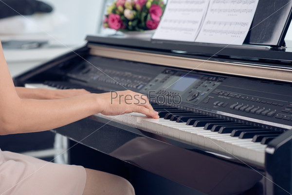 Close-up of woman playing piano, body and buttons of the piano were digitally modified