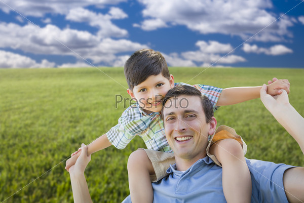 Happy Mixed Race Father and Son Playing Piggyback on Grass Field.