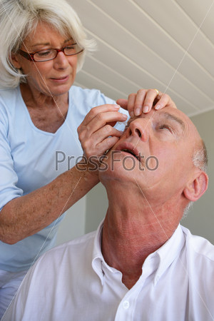 Woman helping husband with contact lenses
