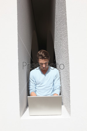 Man using laptop computer by window ledge