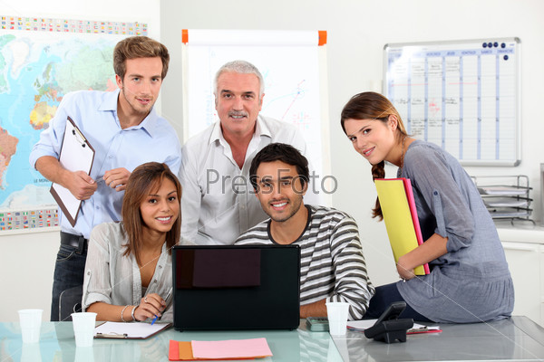 Young team of sitting around a laptop with an older guy